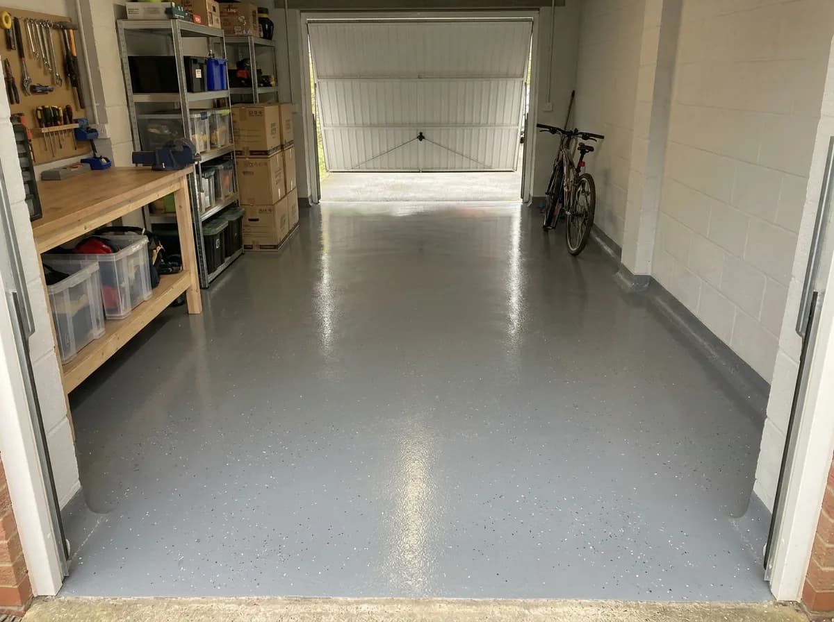 Completed grey epoxy resin floor with decorative flake in a domestic garage, seamless from wall to wall with a coved edge